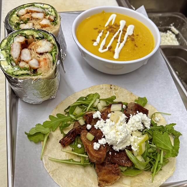 yellow soup, wrap and taco on a plate