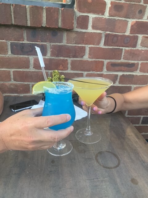 Two colorful cocktails clinking together