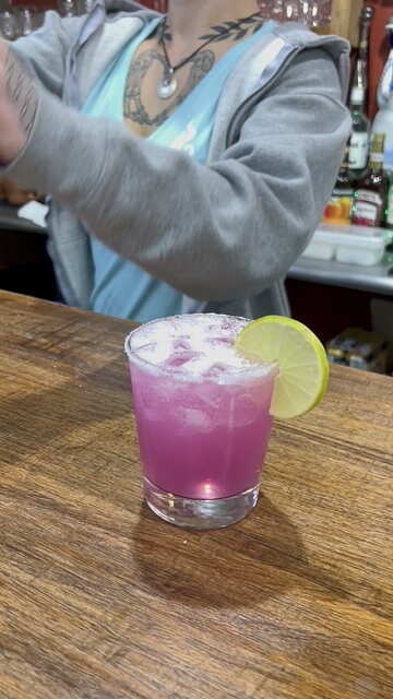 Purple cocktail with lime garnish