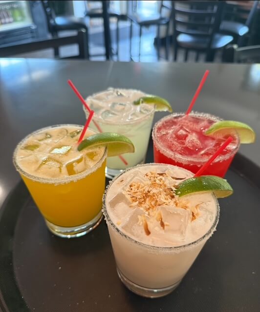 4 different colorful cocktails garnished with lime