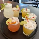 6 unique cocktails on a tray garnished with limes